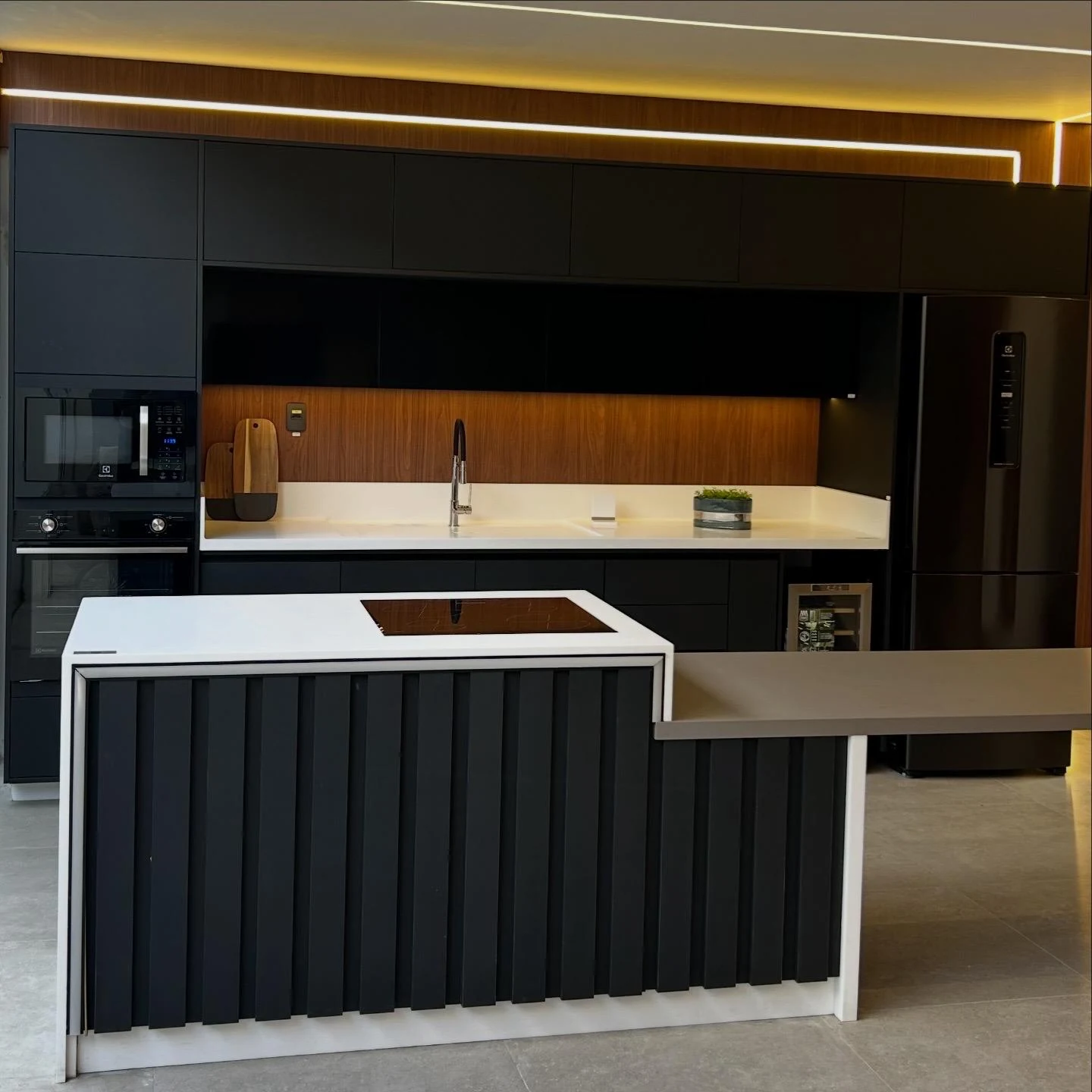Cozinha real com ilha clara e marcenaria escura, em enquadramento completo