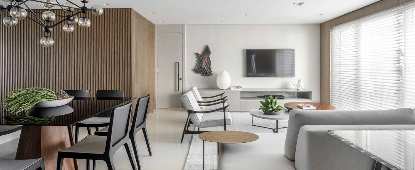 Sala de estar com sofás claros, painel de madeira e marcenaria sob medida