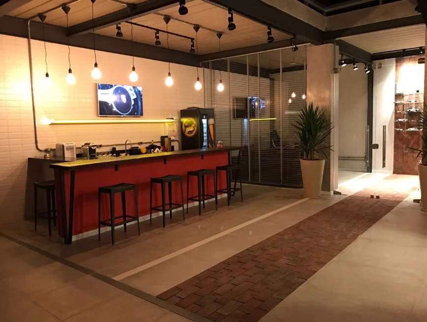 Espaço café real com balcão vermelho, bancos altos e iluminação pendente